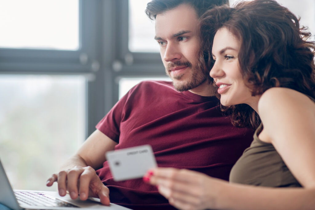 Linda pareja joven que planea comprar algo en línea para acumular millas aéreas y luego vender millas aéreas y obtener ganancias adicionales.